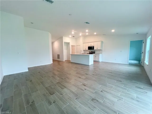 Unfurnished living room with vaulted ceiling, wood finish floors, and recessed lighting