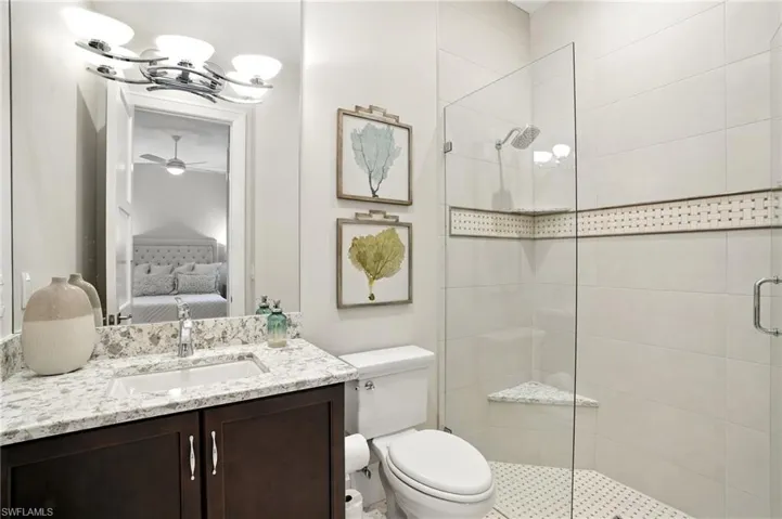 Full bathroom with a stall shower, vanity, ensuite bath, and ceiling fan