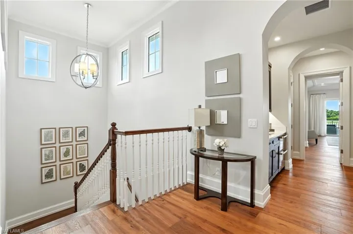 Staircase with hardwood / wood-style flooring, recessed lighting, arched walkways, and a chandelier