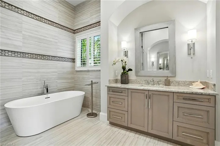 Full bath featuring a freestanding bath, tile walls, and vanity