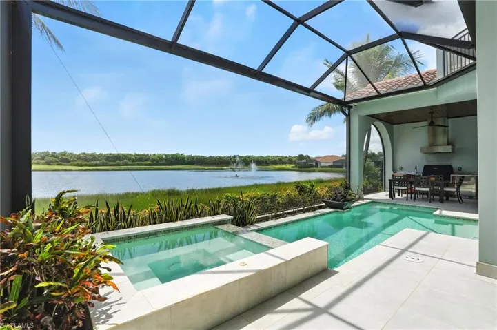 View of pool featuring a ceiling fan, a water view, a patio, a pool with connected hot tub, and a sunroom