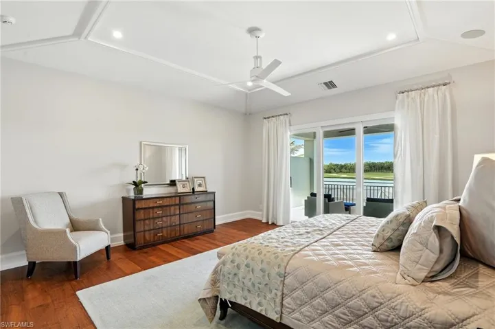 Bedroom featuring wood finished floors, access to exterior, ceiling fan, a water view, and recessed lighting