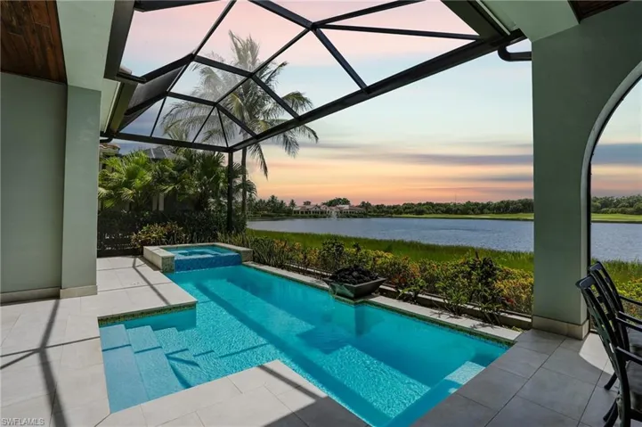 View of swimming pool featuring a patio, glass enclosure, a pool with connected hot tub, and a sunroom
