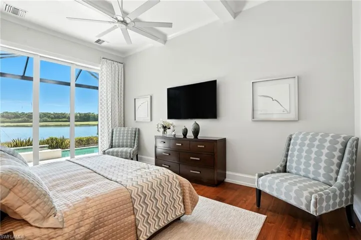 Bedroom featuring dark wood-type flooring, beamed ceiling, access to exterior, and ceiling fan