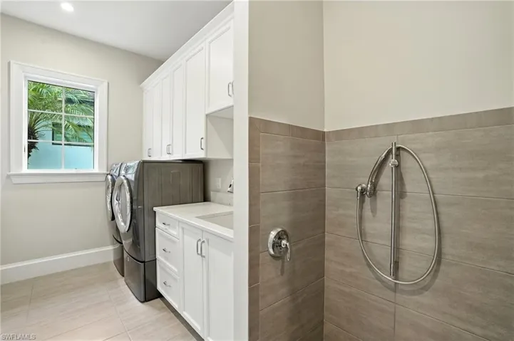 Laundry room featuring washer and clothes dryer and light tile patterned flooring