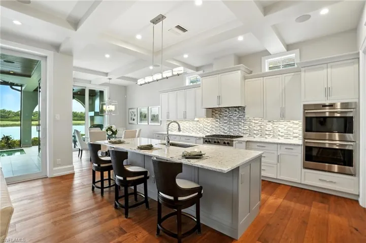 Kitchen with coffered ceiling, beam ceiling, healthy amount of natural light, stainless steel appliances, and decorative backsplash