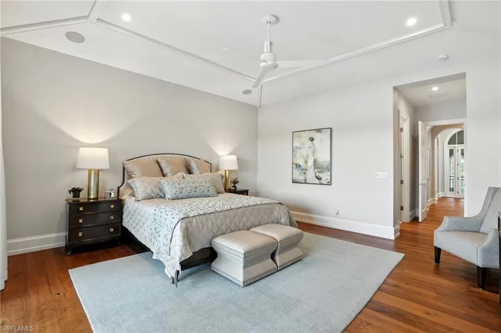 Bedroom with dark wood-style floors, recessed lighting, arched walkways, and ceiling fan