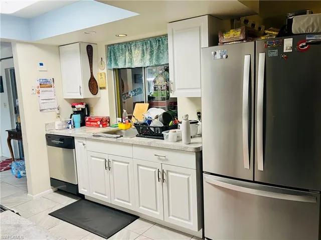 Kitchen featuring appliances with stainless steel finishes, white cabinetry, light countertops, and light tile patterned floors