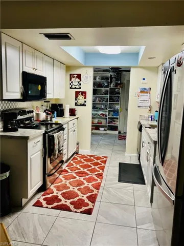 Kitchen featuring white cabinetry, stainless steel appliances, light countertops, and light tile patterned floors