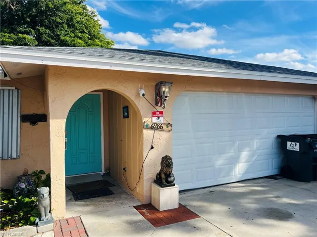 Doorway to property with stucco siding, a shingled roof, and concrete driveway