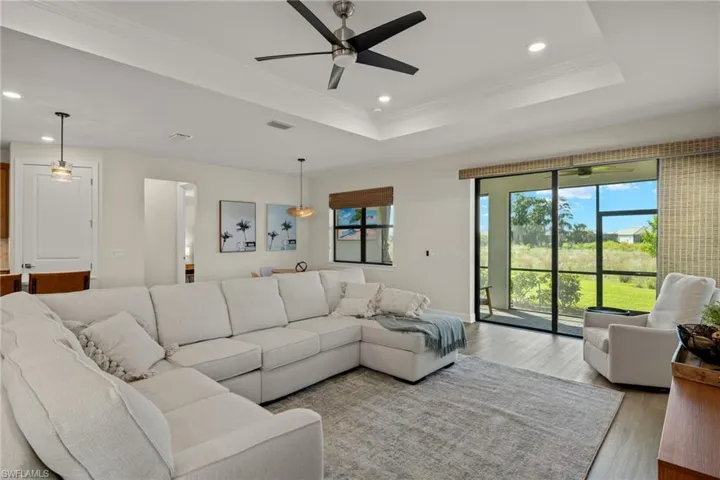 Living room with crown molding, a tray ceiling, ceiling fan, and hardwood / wood-style flooring