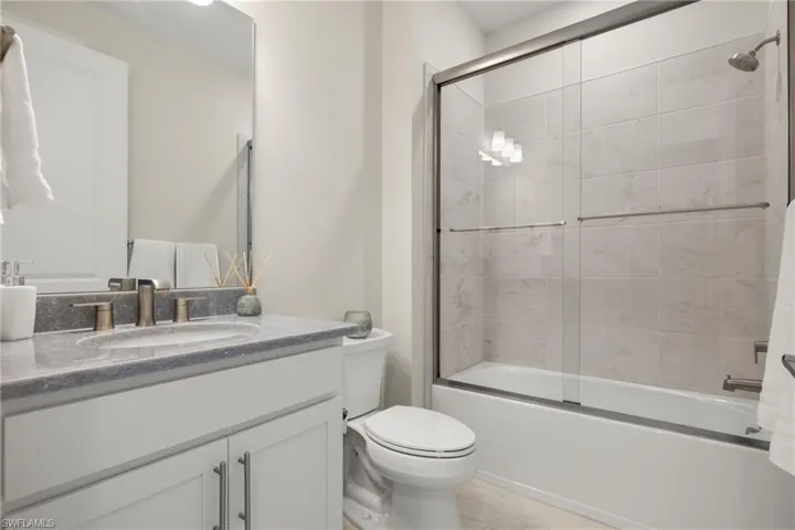 Full bathroom featuring shower / bath combination with glass door, vanity, and toilet