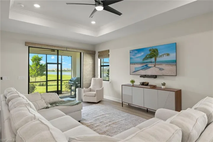 Living room featuring a raised ceiling, ornamental molding, ceiling fan, and hardwood / wood-style flooring