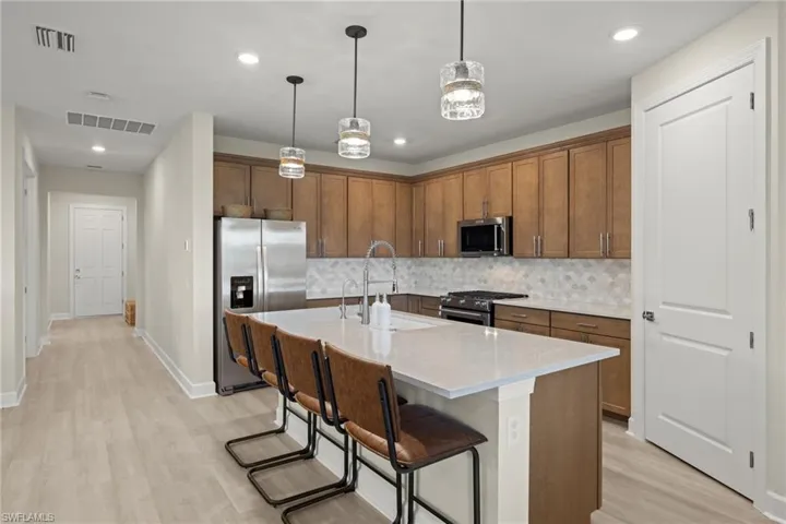 Kitchen with appliances with stainless steel finishes, an island with sink, a breakfast bar, light wood-type flooring, and sink