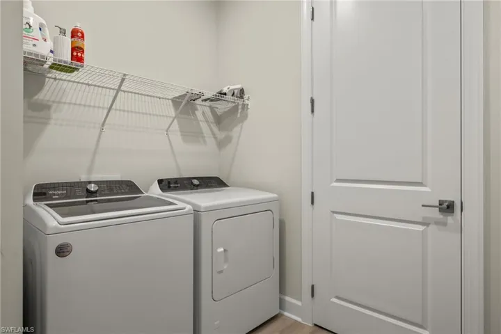 Clothes washing area with light wood-type flooring and independent washer and dryer