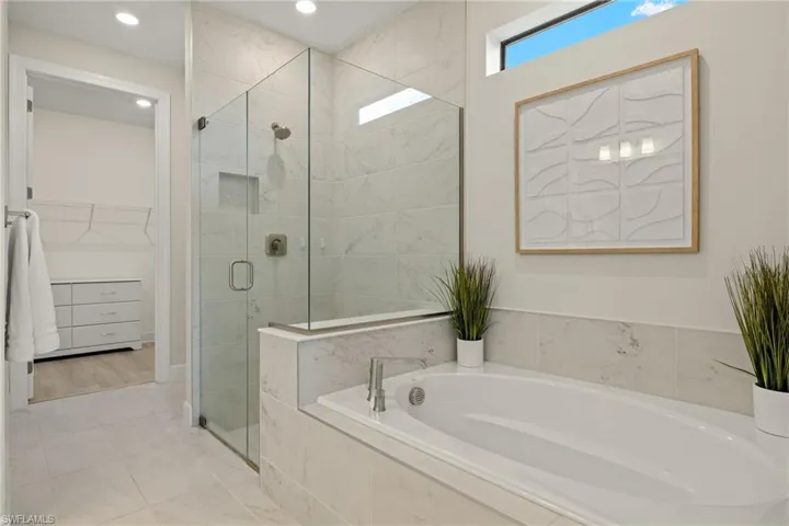 Bathroom with shower with separate bathtub and tile patterned flooring