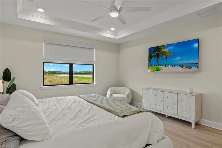 Bedroom featuring ceiling fan, light hardwood / wood-style flooring, crown molding, and a raised ceiling