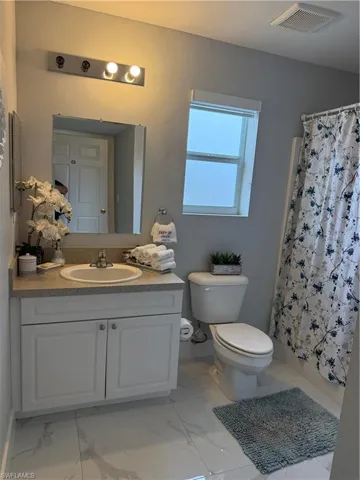 Full bath featuring vanity and light marble finish floors