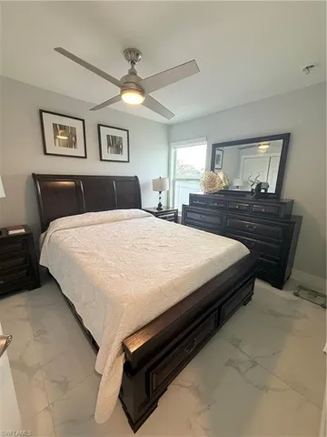 Bedroom featuring a ceiling fan and light marble finish floors