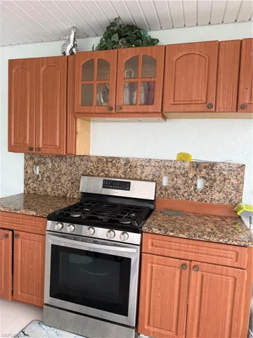 Kitchen with stove, dark stone counters, glass insert cabinets, and wood finish cabinetry
