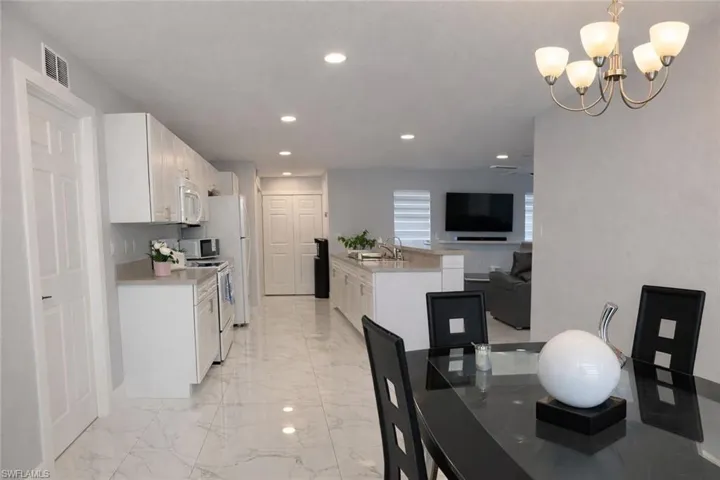 Kitchen with white cabinetry, a peninsula, open floor plan, electric range oven, and white microwave