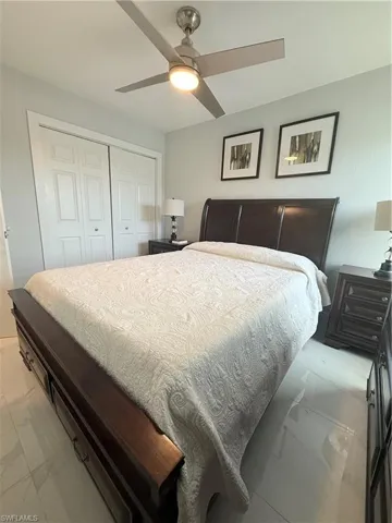 Bedroom featuring a closet, light marble finish flooring, and a ceiling fan