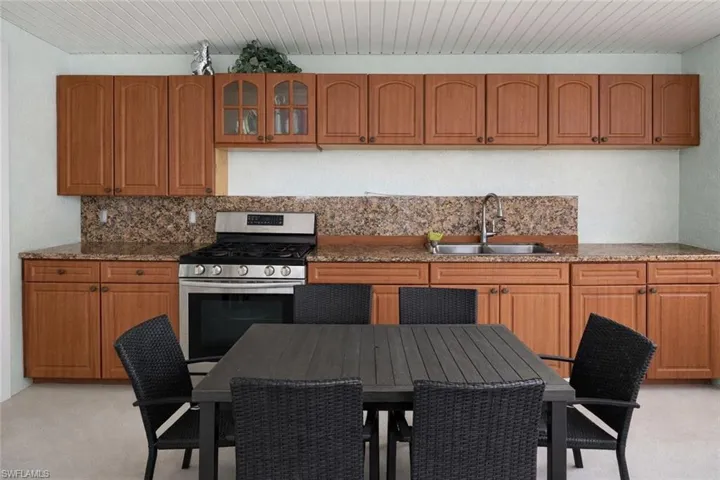 Kitchen featuring wood finish cabinetry, stainless steel gas range, glass fronted cabinets, and dark stone counters