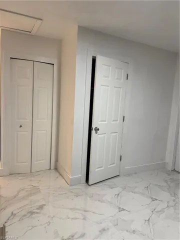 Unfurnished bedroom featuring a closet and light marble finish floors