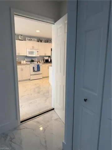 Kitchen featuring white cabinets, range, light marble finish floors, light countertops, and recessed lighting