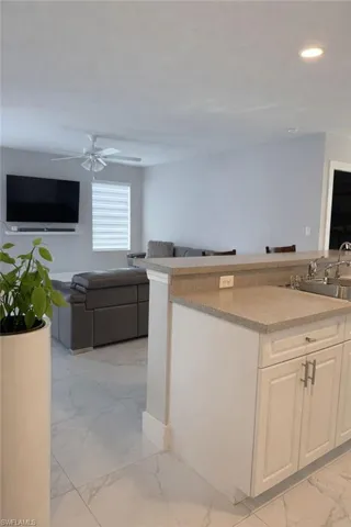 Kitchen featuring open floor plan, light marble finish floors, white cabinetry, ceiling fan, and recessed lighting