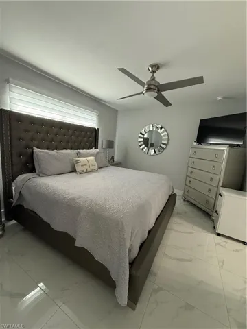 Bedroom featuring light marble finish floors and a ceiling fan