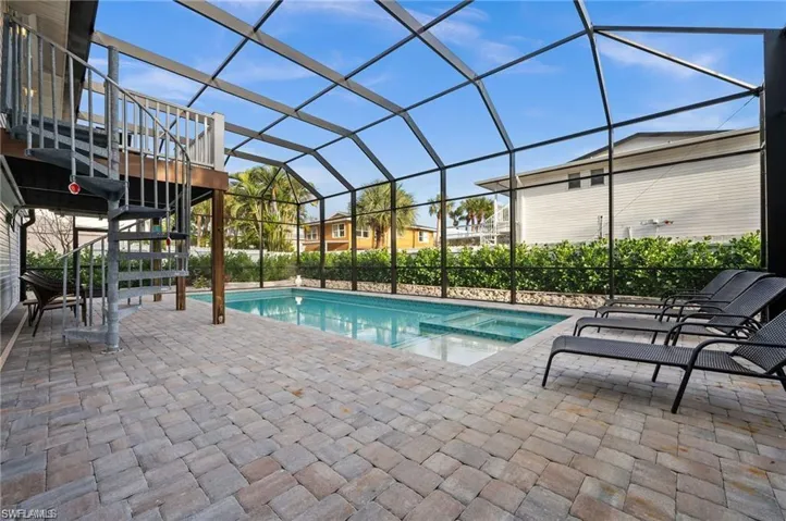 View of pool featuring glass enclosure and a patio