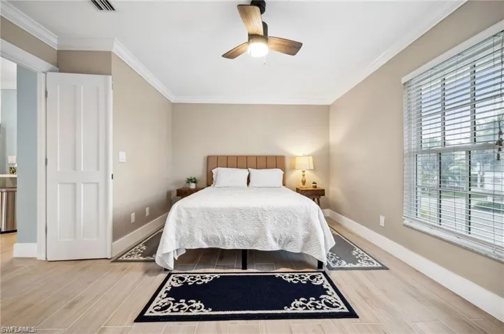 Bedroom featuring multiple windows, ceiling fan, hardwood / wood-style floors, and ornamental molding
