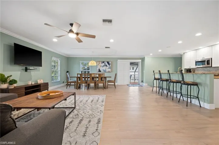 Living room featuring crown molding, light hardwood / wood-style flooring, and ceiling fan