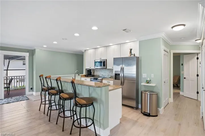 Kitchen with white cabinets, stainless steel appliances, light hardwood / wood-style floors, and a breakfast bar area