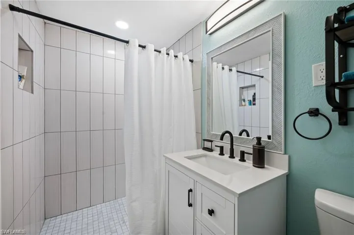 Bathroom with toilet, vanity, and walk in shower