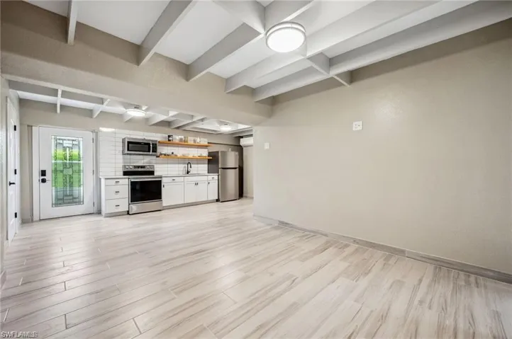 Unfurnished living room featuring beam ceiling, light hardwood / wood-style floors, and sink