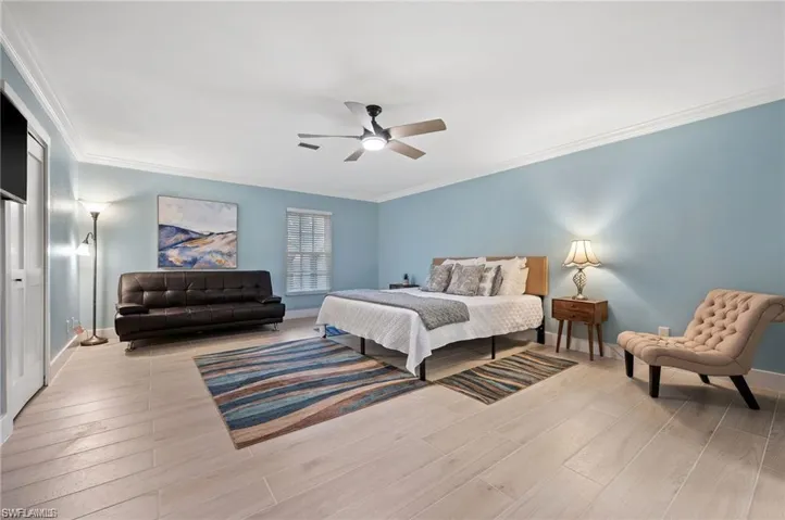 Bedroom with ceiling fan, light hardwood / wood-style flooring, and ornamental molding