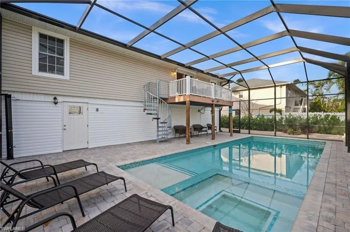 View of swimming pool with a lanai, a patio area, and an in ground hot tub