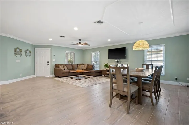 Dining space with ceiling fan, light hardwood / wood-style floors, and ornamental molding