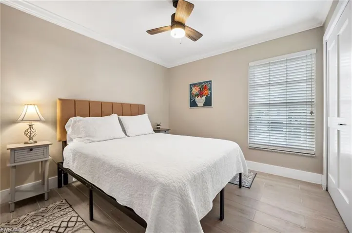 Bedroom featuring ceiling fan, light wood-type flooring, ornamental molding, and a closet