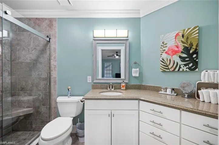 Bathroom with an enclosed shower, ornamental molding, vanity, ceiling fan, and toilet