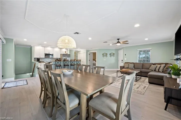 Dining space with ceiling fan, light hardwood / wood-style floors, and ornamental molding