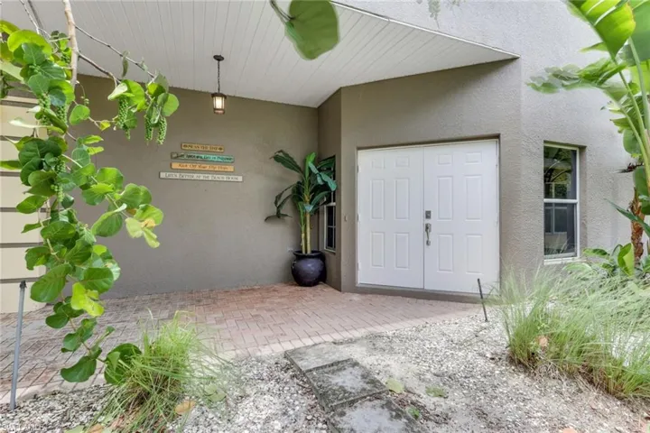 Entryway featuring double white paneled doors, a covered brick paver porch, and a hanging exterior light fixture