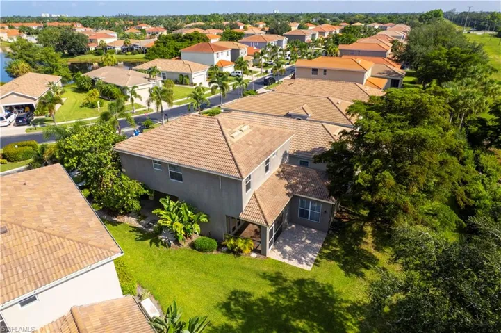 Aerial perspective showcasing a tiled-roof residence with a screened patio and private backyard, surrounded by lush landscaping and a manicured lawn
