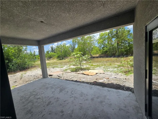 Concrete patio with textured ceiling, supported by a concrete pillar, opening to an expansive outdoor area