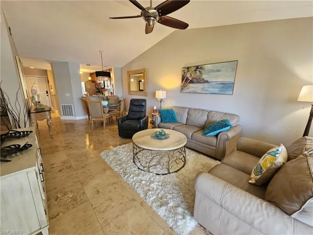 Tiled living room with lofted ceiling and ceiling fan