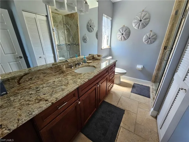 Bathroom featuring tile floors, walk in shower, toilet, and large vanity