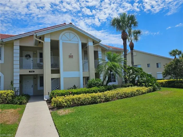 View of front of property featuring a front yard and a balcony