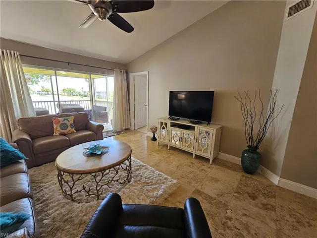 Living room featuring tile floors, ceiling fan, and lofted ceiling